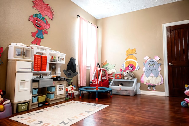 game room with a textured ceiling, wood finished floors, and baseboards