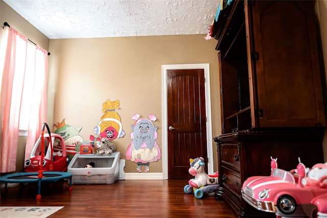 bedroom with a textured ceiling, baseboards, and wood finished floors