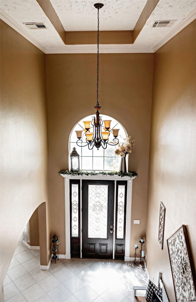 foyer entrance with a raised ceiling, a notable chandelier, a towering ceiling, and light tile patterned floors