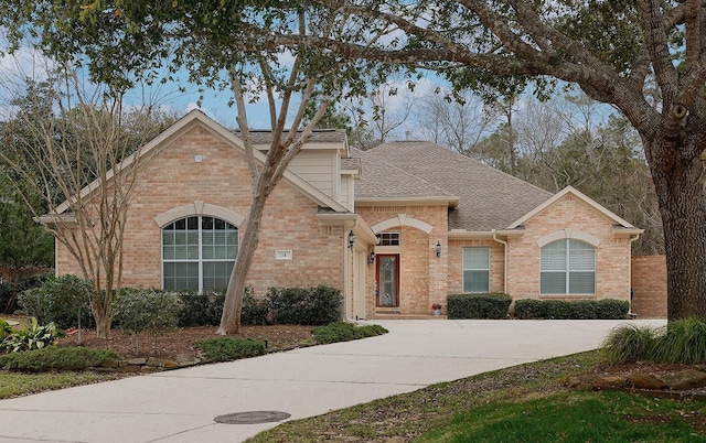 traditional-style home featuring a shingled roof and brick siding