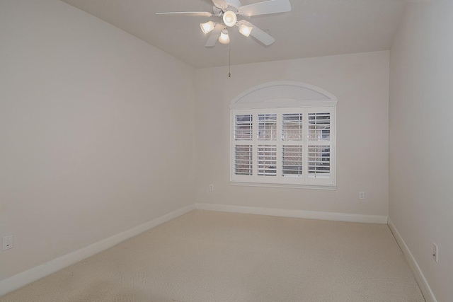 carpeted spare room with a ceiling fan and baseboards