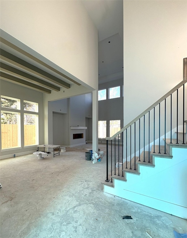 stairway with beam ceiling, a fireplace, and a high ceiling