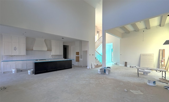 unfurnished living room featuring beam ceiling, concrete floors, stairway, and a towering ceiling