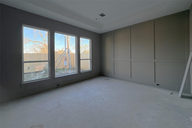 spare room featuring visible vents, unfinished concrete flooring, and a decorative wall