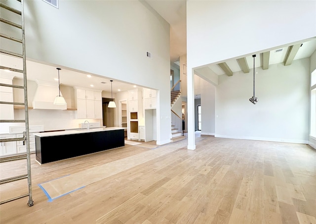1953 Coulcrest Dr, Houston, TX 77055 - unfurnished living room featuring a sink, a high ceiling, light wood-style floors, stairway, and beamed ceiling