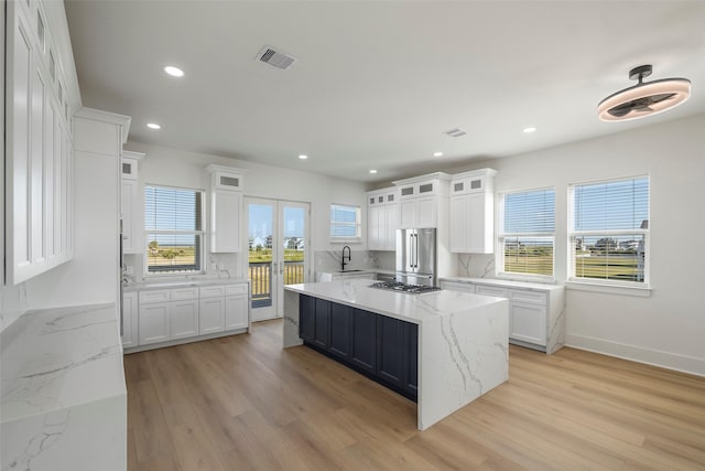 kitchen with tasteful backsplash, visible vents, light wood-style flooring, white cabinets, and high end refrigerator