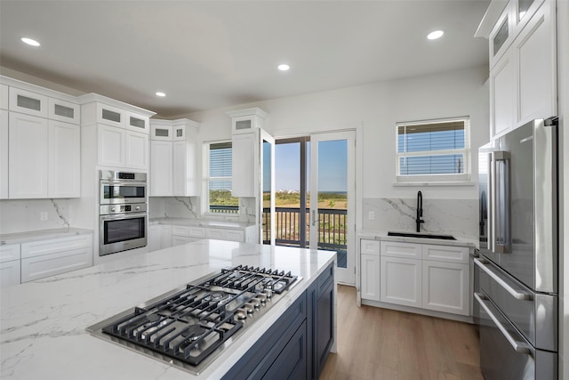 kitchen featuring appliances with stainless steel finishes, white cabinets, a sink, and tasteful backsplash