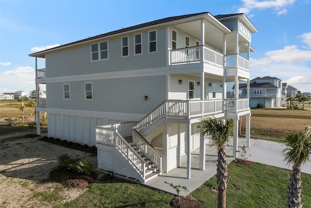 rear view of house featuring stairs, driveway, and a porch