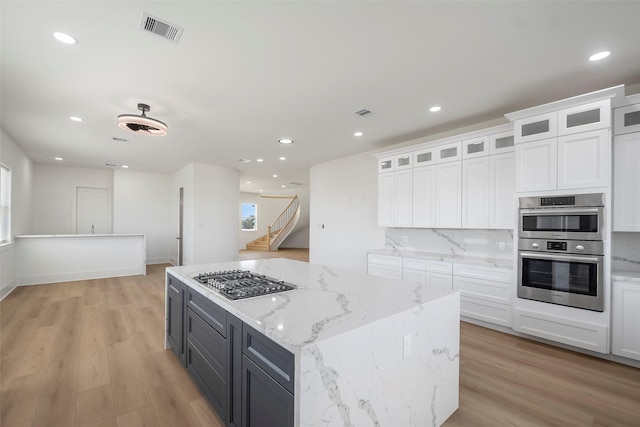 kitchen featuring stainless steel appliances, white cabinets, visible vents, and light wood-style flooring