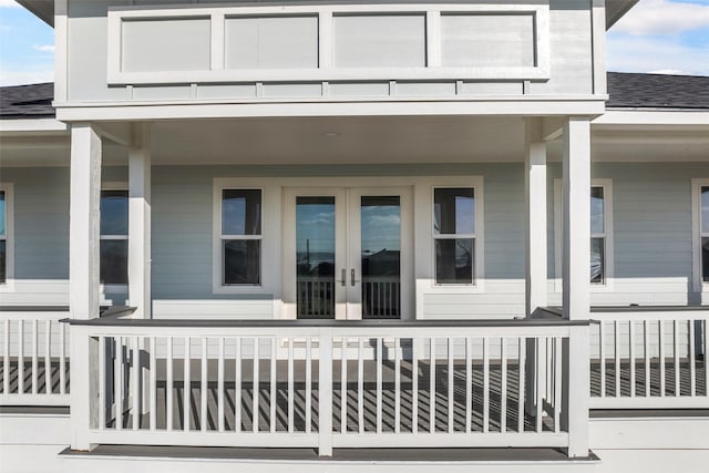 view of exterior entry featuring french doors and roof with shingles