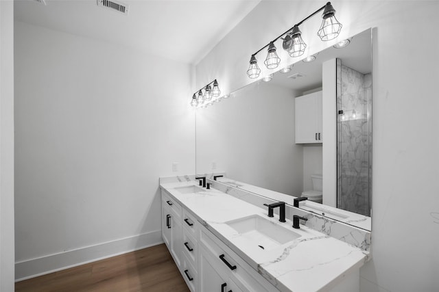 bathroom featuring visible vents, toilet, a sink, wood finished floors, and baseboards