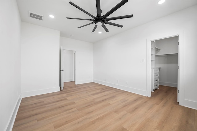 unfurnished bedroom featuring light wood finished floors, baseboards, visible vents, a spacious closet, and recessed lighting