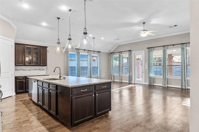 kitchen featuring wood finished floors, a sink, dark brown cabinets, ornamental molding, and decorative light fixtures