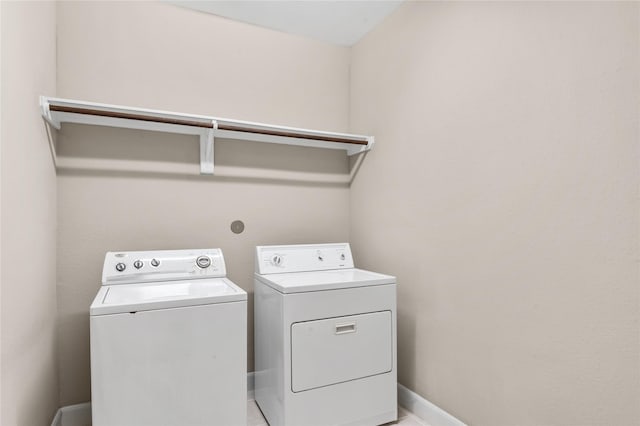 clothes washing area featuring laundry area, washing machine and clothes dryer, and baseboards