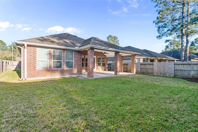 rear view of property with a ceiling fan, a lawn, a patio, a fenced backyard, and brick siding