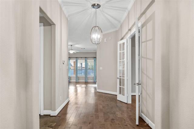 hallway featuring a notable chandelier, dark wood-type flooring, baseboards, french doors, and ornamental molding