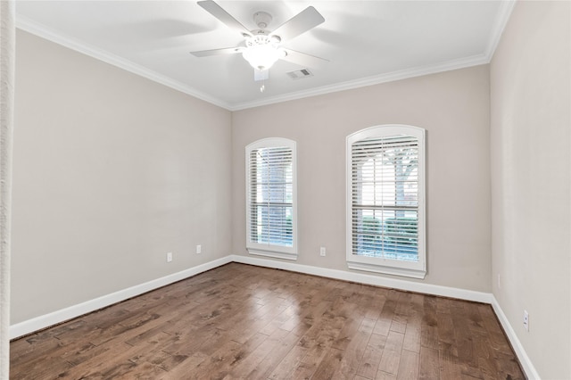 empty room featuring baseboards, wood finished floors, visible vents, and crown molding