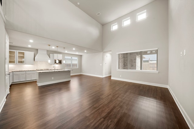 unfurnished living room with dark wood-type flooring, plenty of natural light, and baseboards