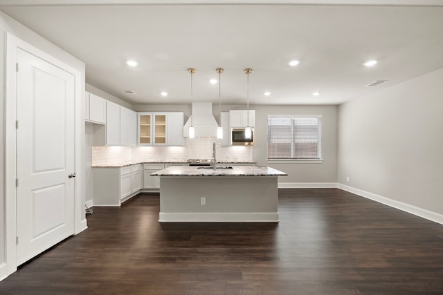 kitchen with visible vents, dark wood finished floors, decorative backsplash, custom range hood, and stainless steel microwave