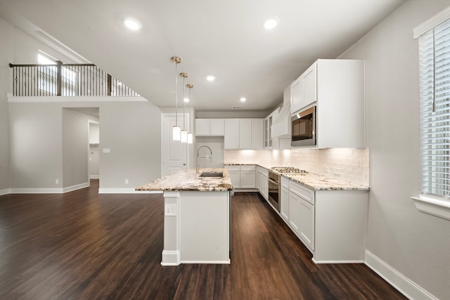 kitchen with light stone counters, stainless steel appliances, dark wood-type flooring, and a sink