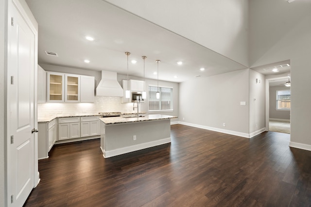 kitchen featuring dark wood finished floors, stainless steel appliances, visible vents, a sink, and premium range hood