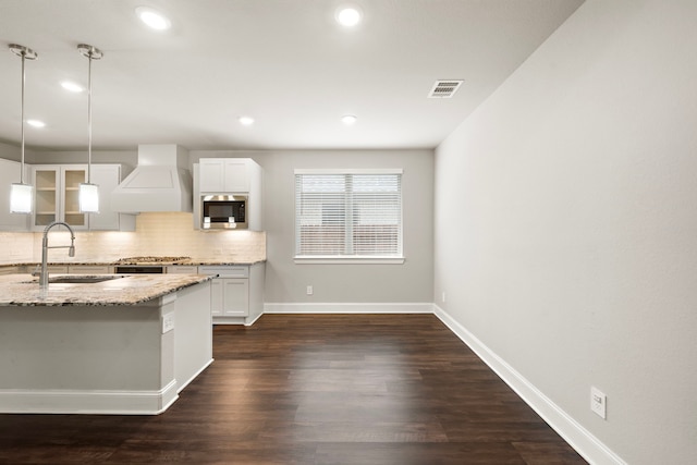 kitchen featuring a sink, visible vents, custom exhaust hood, tasteful backsplash, and stainless steel microwave