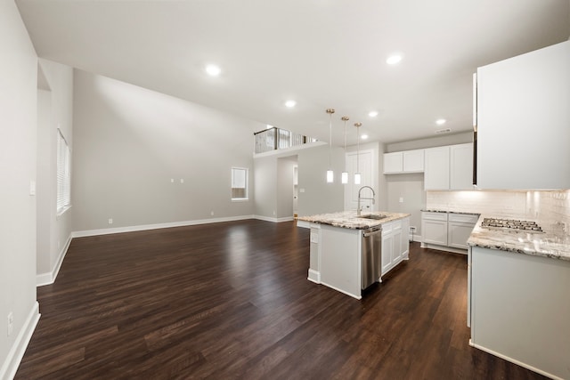 kitchen with tasteful backsplash, dark wood-style floors, appliances with stainless steel finishes, open floor plan, and a sink