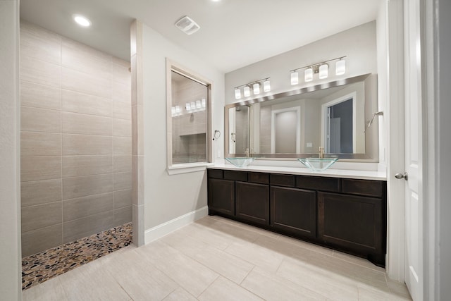 full bathroom featuring double vanity, visible vents, baseboards, tile patterned floors, and walk in shower