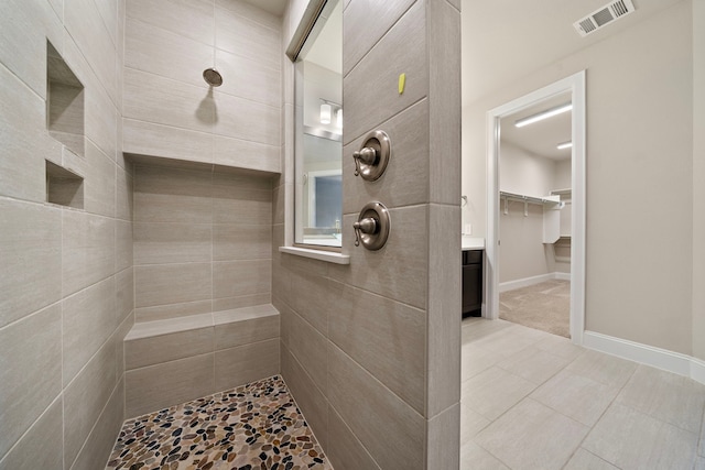 bathroom with visible vents, baseboards, and tiled shower