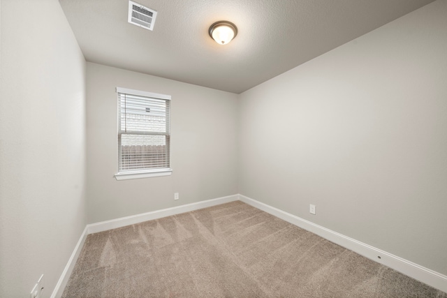 unfurnished room with light carpet, baseboards, visible vents, and a textured ceiling