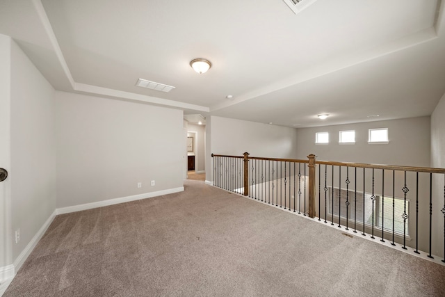 carpeted spare room featuring visible vents and baseboards