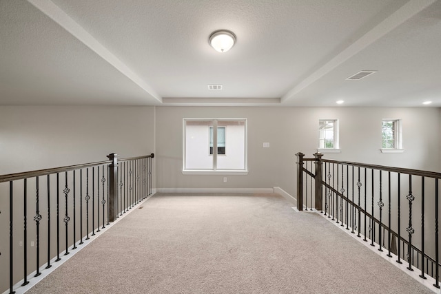 carpeted spare room with a textured ceiling, visible vents, and baseboards