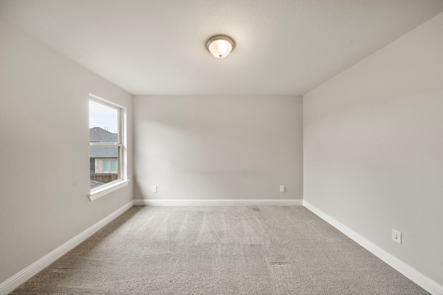 spare room featuring carpet and baseboards