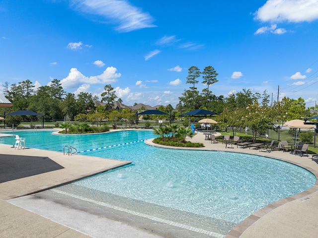 community pool with a patio area and fence