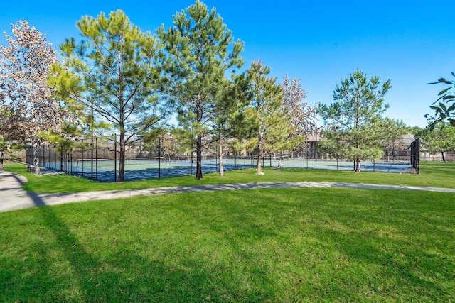 view of home's community with a tennis court, a lawn, and fence