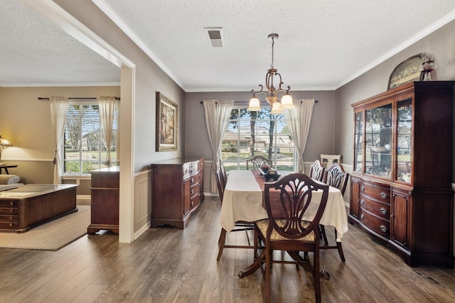 dining area featuring ornamental molding, dark wood-style flooring, a wealth of natural light, and an inviting chandelier