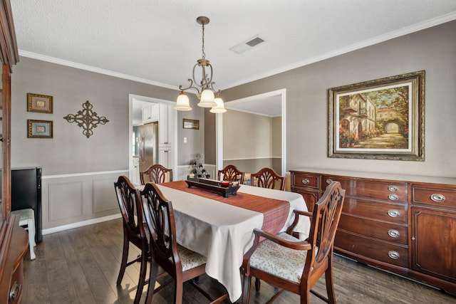 dining area featuring visible vents, wainscoting, ornamental molding, dark wood-style flooring, and a textured ceiling