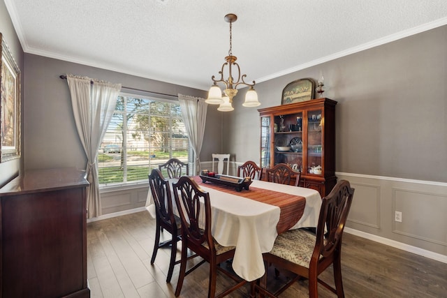 dining room featuring a textured ceiling, a chandelier, wood finished floors, and ornamental molding