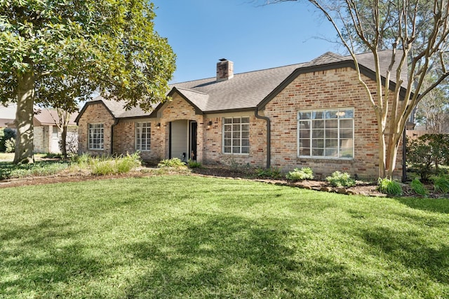 view of front of home with a front yard, roof with shingles, a chimney, and brick siding