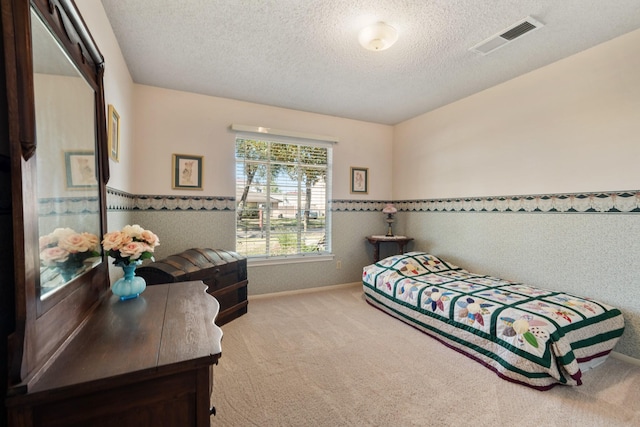 bedroom with carpet floors, a wainscoted wall, visible vents, and a textured ceiling