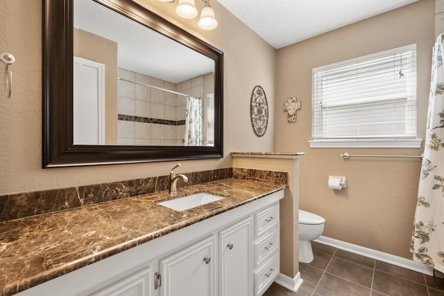 bathroom with tile patterned flooring, toilet, vanity, baseboards, and tiled shower