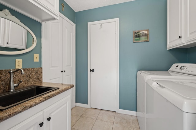 laundry area featuring light tile patterned floors, washing machine and dryer, a sink, baseboards, and cabinet space