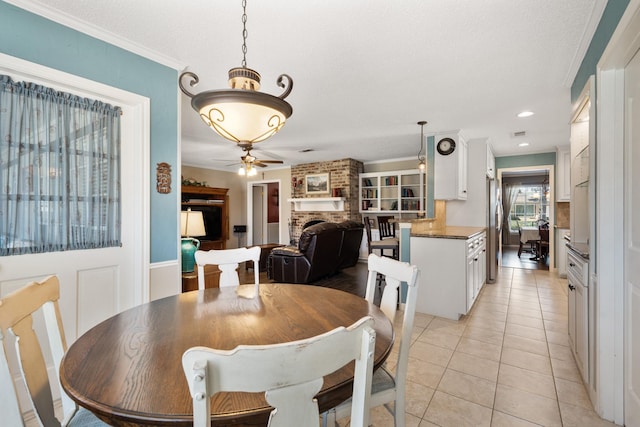 dining area featuring light tile patterned floors, recessed lighting, a fireplace, a ceiling fan, and crown molding