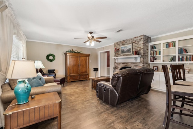 living room with a brick fireplace, wood finished floors, visible vents, and crown molding