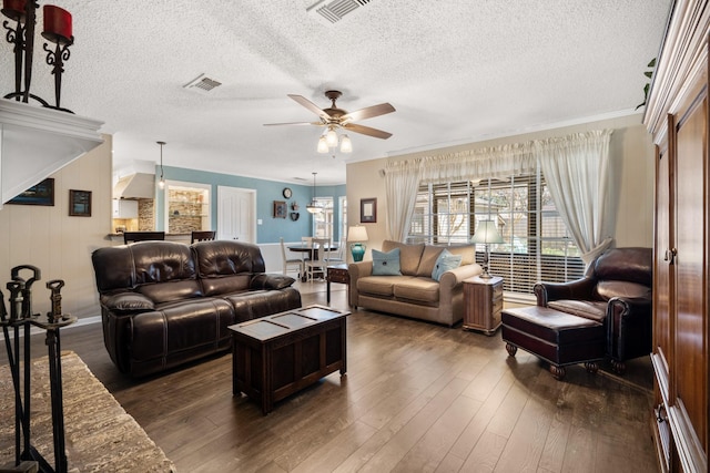 living room with dark wood-style floors, visible vents, and a ceiling fan