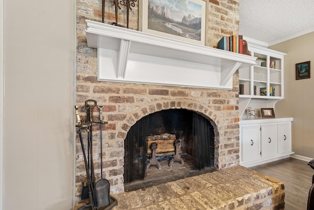 details with a textured ceiling, ornamental molding, a brick fireplace, and wood finished floors