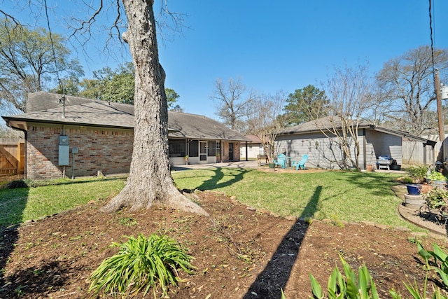 rear view of property featuring a yard, fence, and brick siding