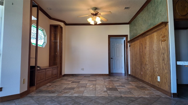 spare room featuring baseboards, a ceiling fan, visible vents, and crown molding