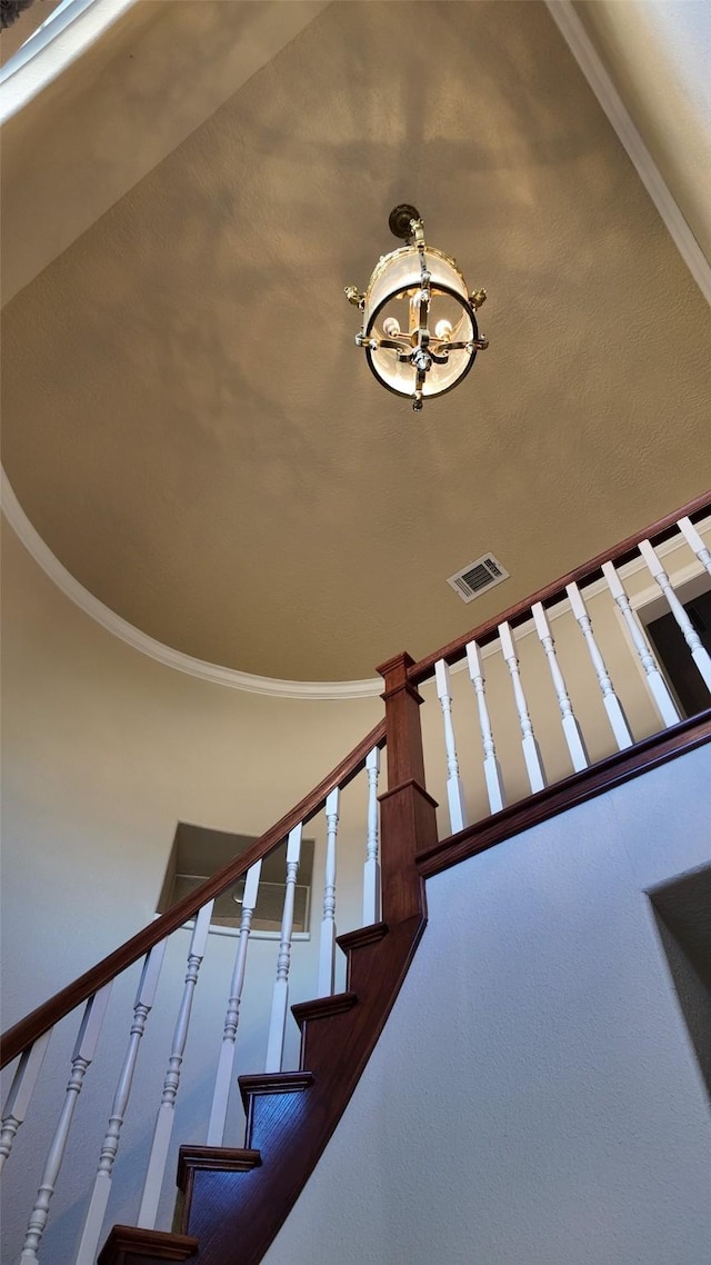 staircase featuring a chandelier, visible vents, and crown molding