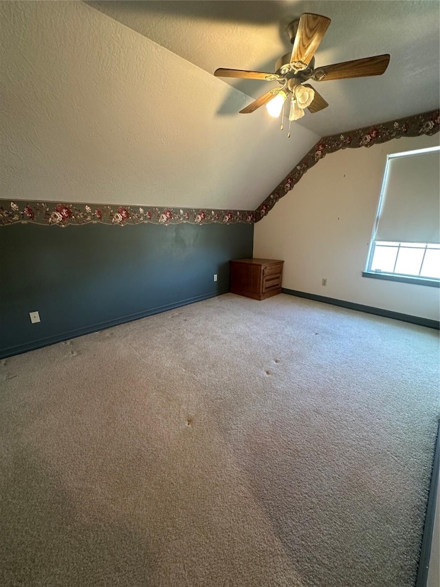 bonus room featuring vaulted ceiling, a textured ceiling, carpet, and a ceiling fan